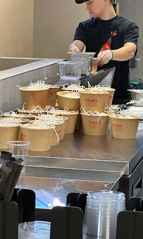 Nón Lá Express cook lining up phở bowls on the kitchen line at Tangram, Flushing