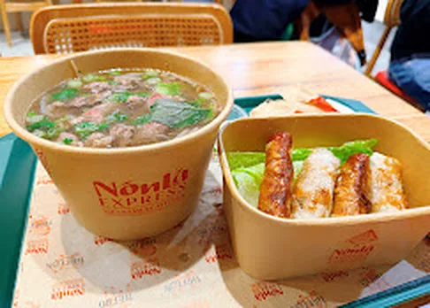 Rare eye round beef phở tái with fresh herbs beside crispy spring rolls at Nón Lá Express Flushing