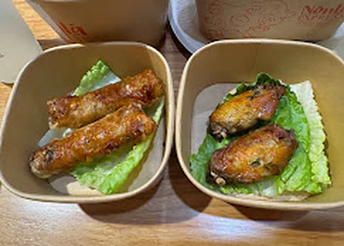Crispy spring rolls and lemongrass chicken wings on lettuce at Nón Lá Express Flushing