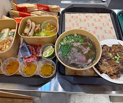 Tray of phở, rice plates, spring rolls and dipping sauces at Nón Lá Express in Flushing, Queens